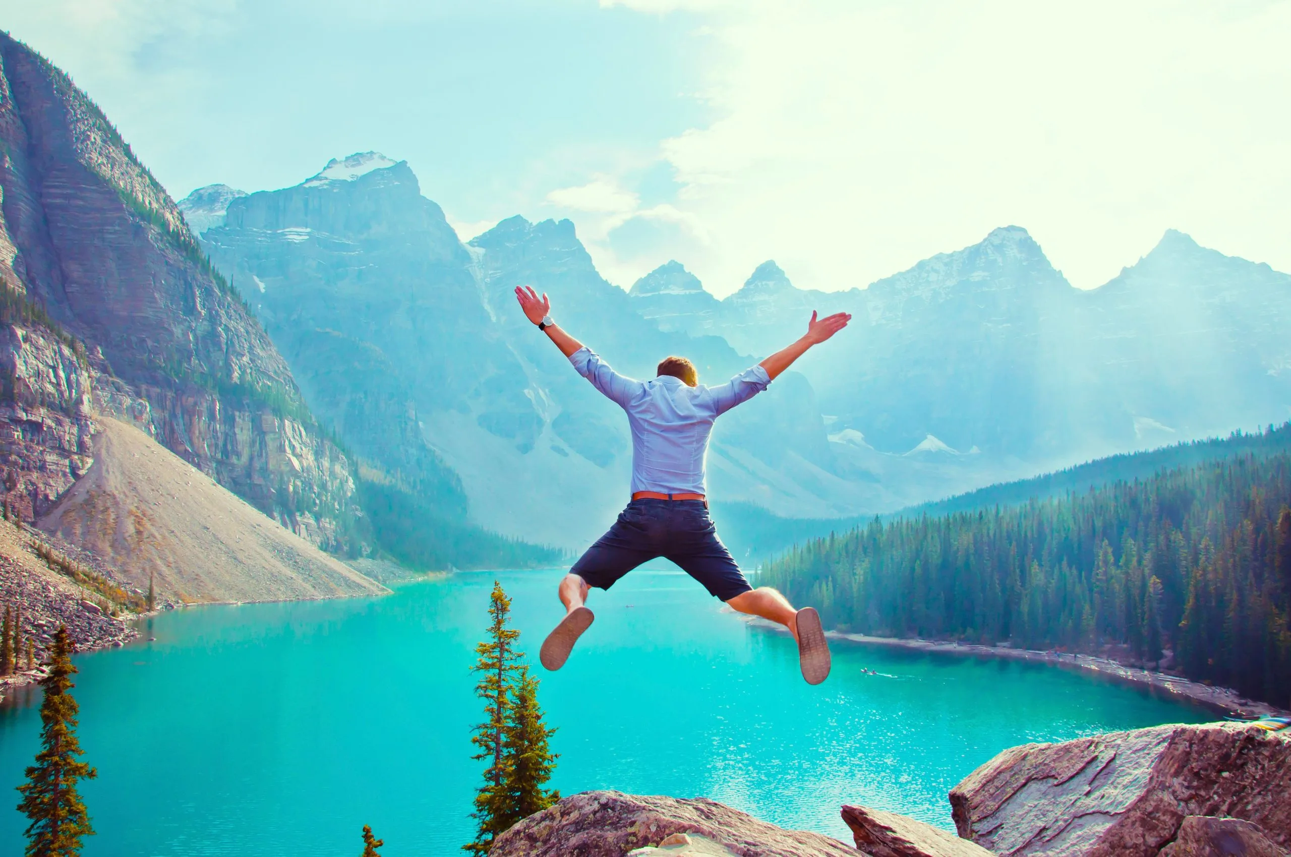 Man happily jumping into a deep blue lake